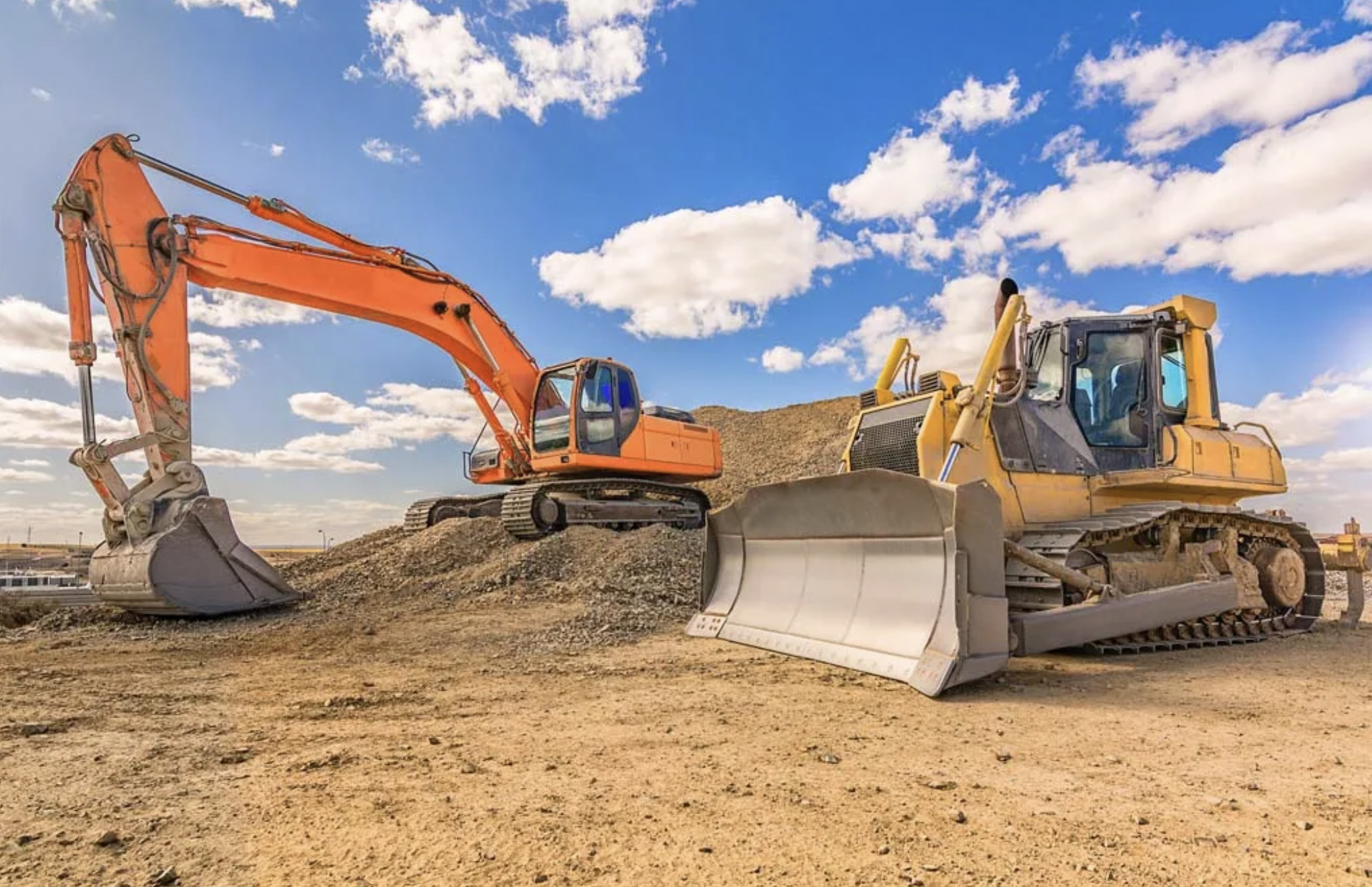Excavator and bulldozer preparing a land clearing and grading site under a blue sky
